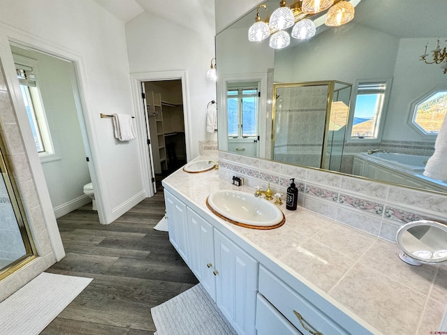 full bathroom featuring separate shower and tub, hardwood / wood-style flooring, vaulted ceiling, toilet, and vanity