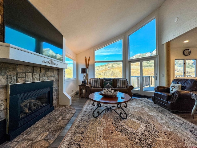 living room with a stone fireplace, a textured ceiling, a mountain view, high vaulted ceiling, and dark hardwood / wood-style floors