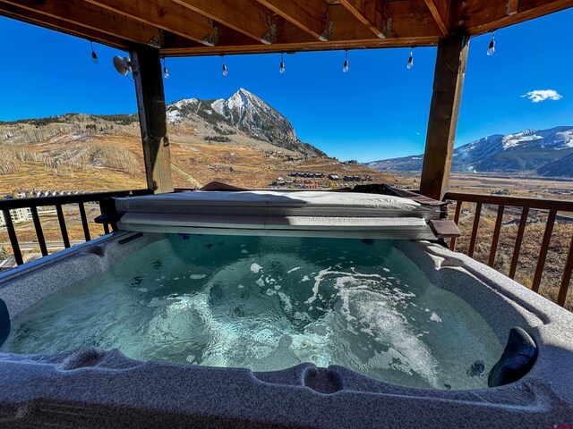 view of swimming pool with a mountain view and a hot tub