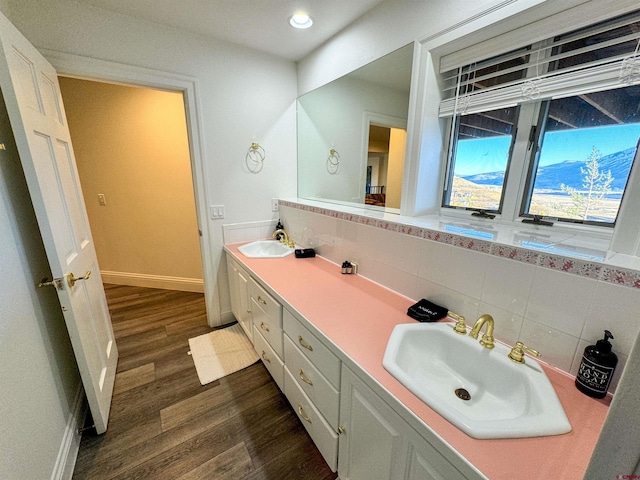 full bath with tasteful backsplash, double vanity, a sink, and wood finished floors