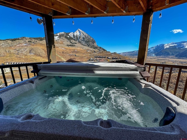 view of swimming pool with a mountain view and a hot tub