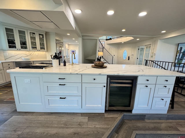 kitchen featuring a breakfast bar area, white cabinetry, an island with sink, and beverage cooler