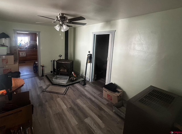 living room featuring a wood stove, wood-type flooring, and ceiling fan