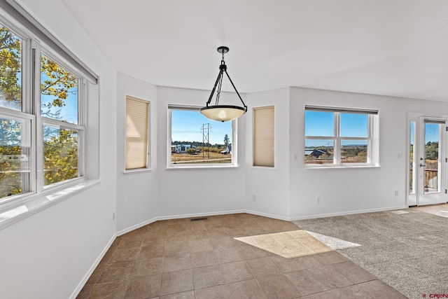 unfurnished dining area with light colored carpet and plenty of natural light