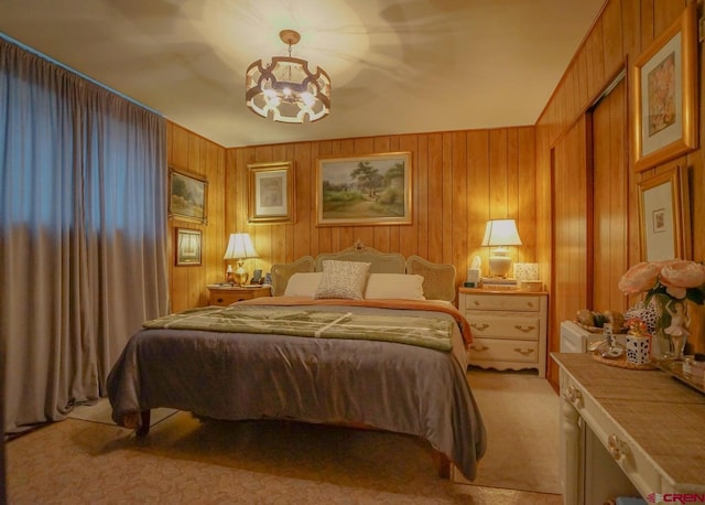 bedroom featuring light carpet, a chandelier, and wooden walls