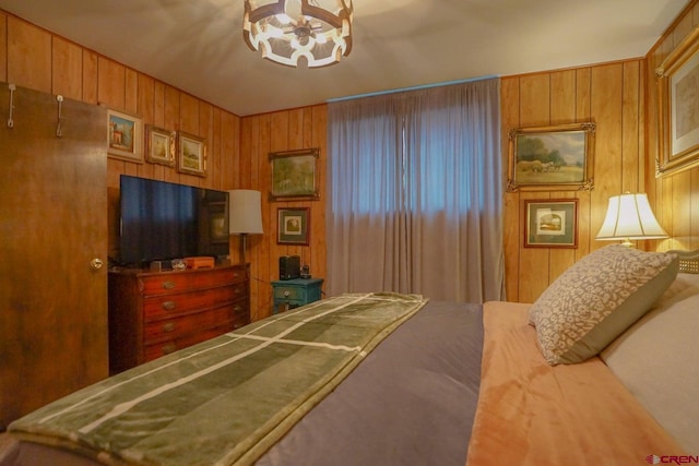 bedroom with a notable chandelier and wood walls