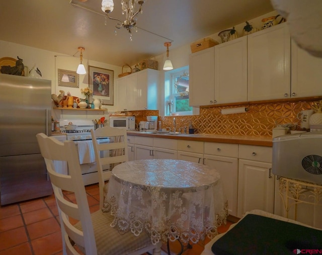 kitchen featuring white cabinetry, tasteful backsplash, hanging light fixtures, and white appliances