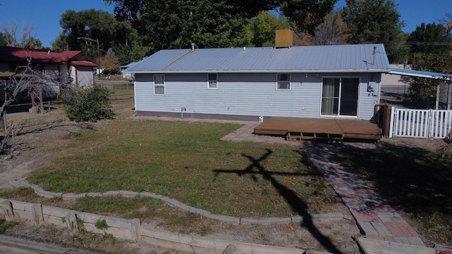 rear view of house featuring a wooden deck and a lawn