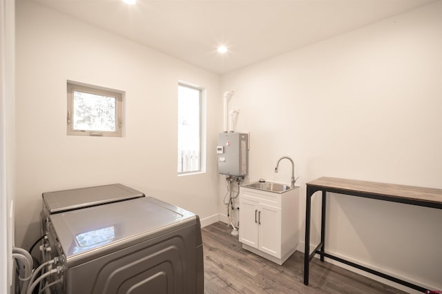 laundry area featuring sink, washer and dryer, wood-type flooring, and cabinets