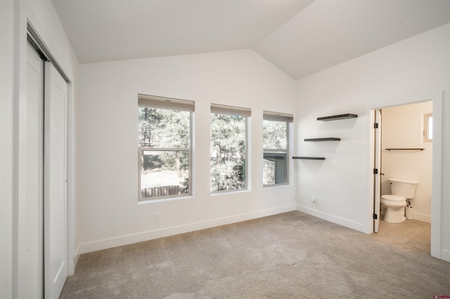 unfurnished bedroom with lofted ceiling, light carpet, ensuite bathroom, and a closet