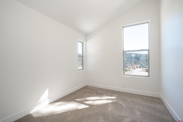 carpeted empty room featuring vaulted ceiling and plenty of natural light