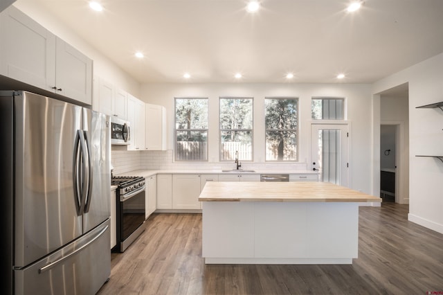 kitchen with hardwood / wood-style floors, a center island, sink, white cabinetry, and appliances with stainless steel finishes