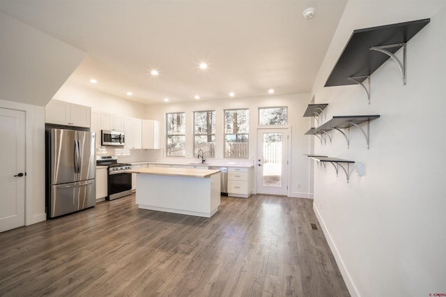 kitchen with kitchen peninsula, tasteful backsplash, dark hardwood / wood-style flooring, appliances with stainless steel finishes, and white cabinetry