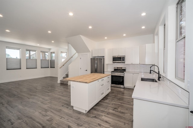 kitchen featuring appliances with stainless steel finishes, dark hardwood / wood-style floors, a center island, and sink