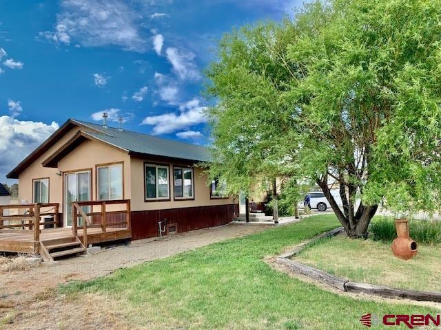 view of side of property with a wooden deck and a yard