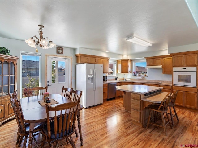 kitchen with a center island, light hardwood / wood-style floors, stainless steel appliances, decorative light fixtures, and an inviting chandelier