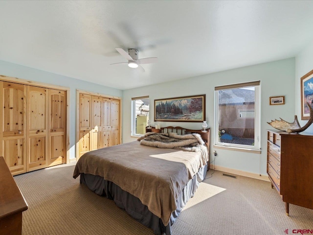 bedroom featuring light carpet, multiple windows, and ceiling fan