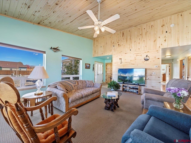 carpeted living room with wooden ceiling, ceiling fan, a towering ceiling, and wooden walls