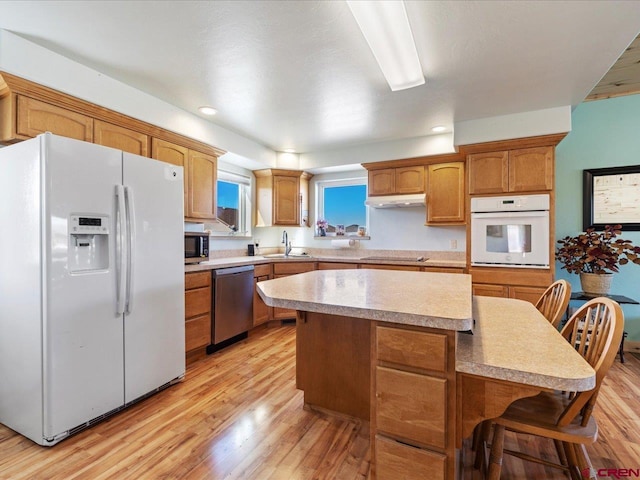 kitchen with light hardwood / wood-style floors, appliances with stainless steel finishes, a breakfast bar, and a center island