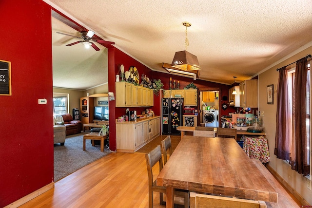 dining room with light hardwood / wood-style flooring, a textured ceiling, washer / clothes dryer, and vaulted ceiling