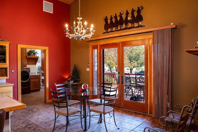 dining area featuring washer / dryer, french doors, a notable chandelier, and a high ceiling