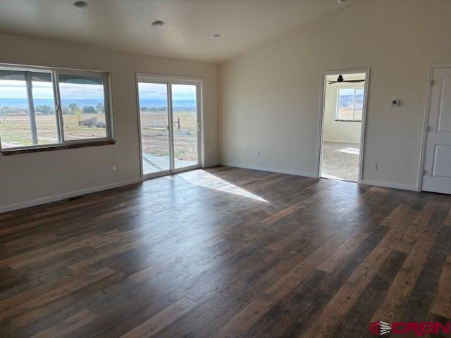 empty room featuring dark hardwood / wood-style flooring, vaulted ceiling, and ceiling fan