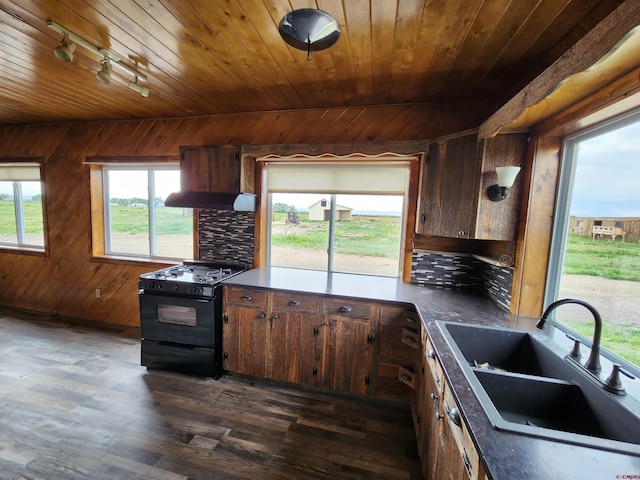 kitchen featuring sink, black range oven, island exhaust hood, wooden walls, and dark wood-type flooring