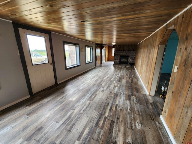 unfurnished living room featuring wood walls, wooden ceiling, dark hardwood / wood-style flooring, and a fireplace