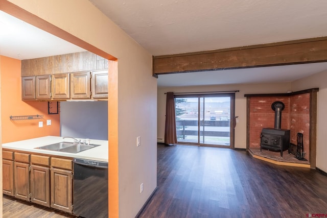 kitchen with black dishwasher, sink, a wood stove, and dark hardwood / wood-style flooring