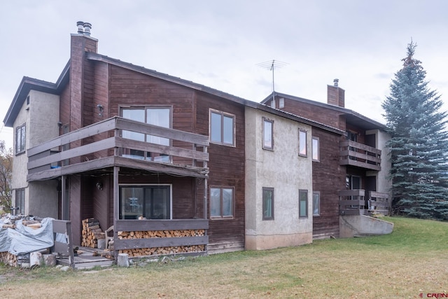 rear view of house with a yard and a balcony