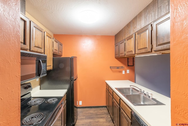 kitchen featuring sink, black appliances, a textured ceiling, and dark hardwood / wood-style flooring