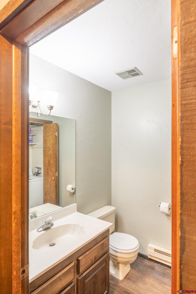 bathroom featuring vanity, toilet, hardwood / wood-style flooring, and baseboard heating