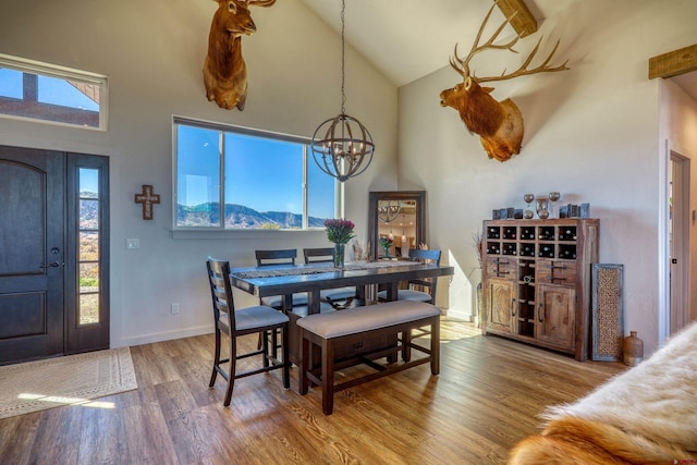 dining space featuring a chandelier, a mountain view, hardwood / wood-style flooring, and high vaulted ceiling