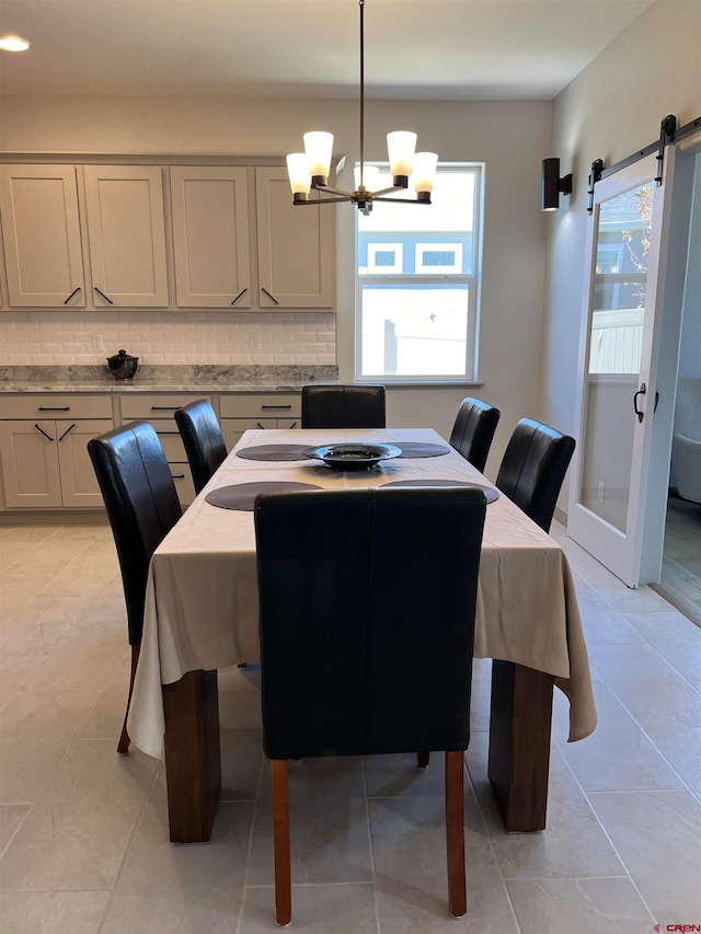 tiled dining room featuring an inviting chandelier and a barn door