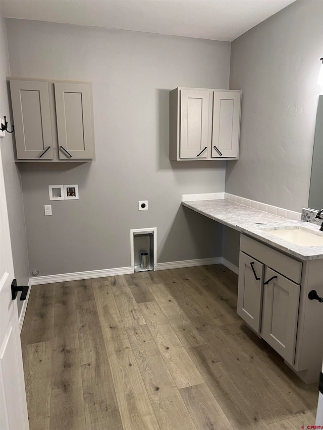 washroom featuring sink, light wood-type flooring, electric dryer hookup, washer hookup, and cabinets