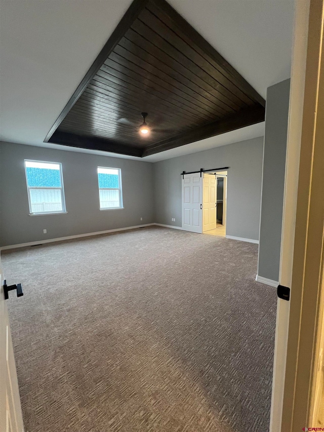 spare room with carpet flooring, wooden ceiling, and a barn door