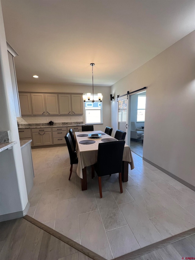 dining area with light hardwood / wood-style floors, an inviting chandelier, and a barn door