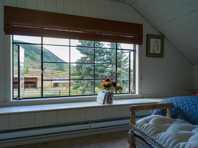 sitting room featuring carpet flooring, plenty of natural light, lofted ceiling, wooden walls, and a mountain view