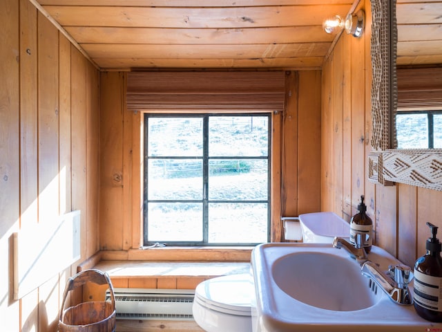 bathroom with toilet, wooden walls, wooden ceiling, sink, and a baseboard radiator