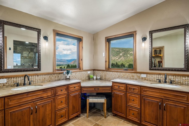 bathroom with lofted ceiling, tasteful backsplash, tiled shower, and vanity