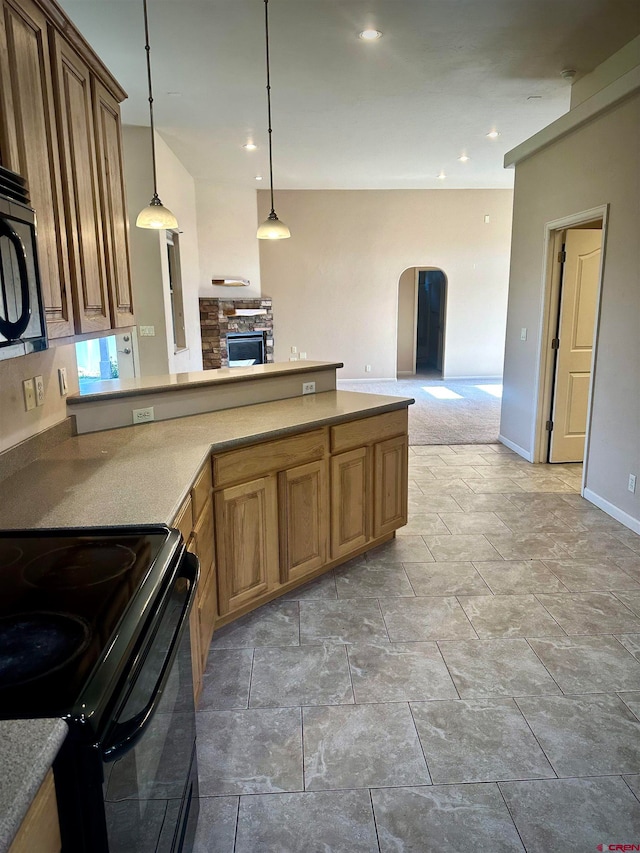 kitchen featuring a fireplace, pendant lighting, and black appliances