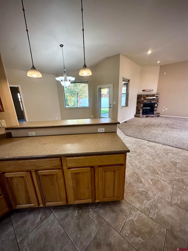 kitchen with pendant lighting, a stone fireplace, and dark colored carpet