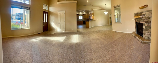 unfurnished living room featuring light carpet, high vaulted ceiling, and a fireplace