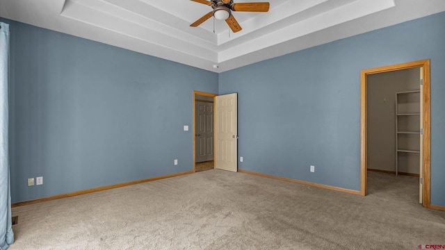 carpeted spare room featuring ceiling fan and a tray ceiling