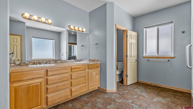 bathroom featuring toilet, vanity, and a shower with door