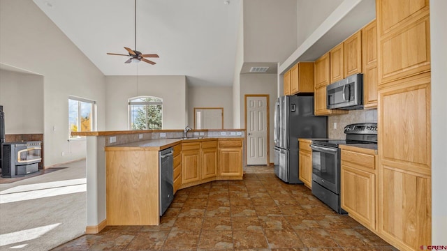 kitchen featuring high vaulted ceiling, stainless steel appliances, light brown cabinets, and dark colored carpet