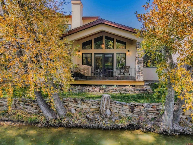 back of property with a chimney and stucco siding