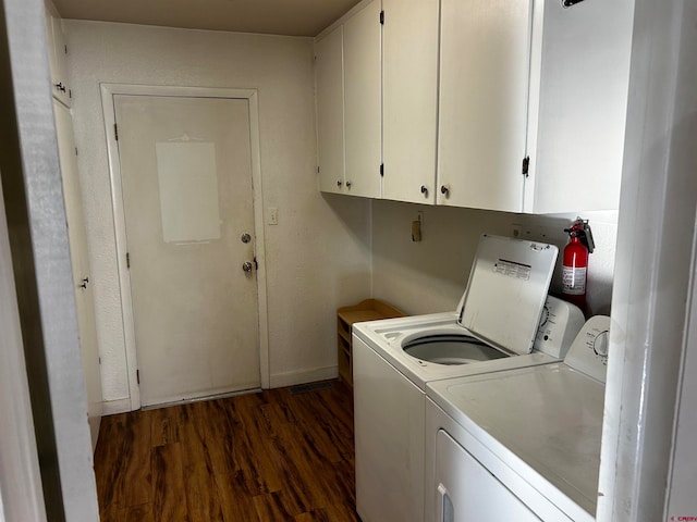 laundry room with dark wood-type flooring, washer and dryer, and cabinets