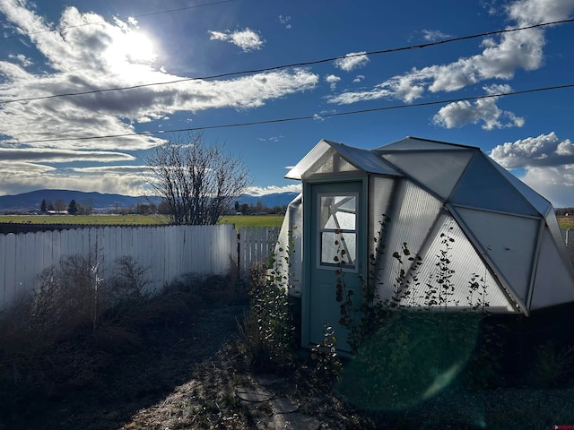 view of side of home with a mountain view and a storage shed