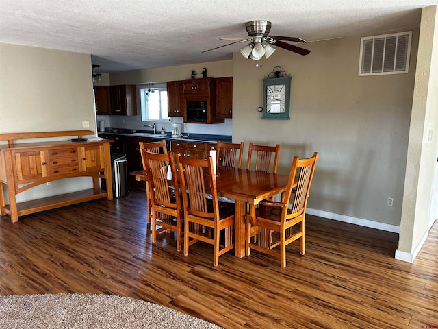 dining space with a textured ceiling, ceiling fan, sink, and dark hardwood / wood-style flooring